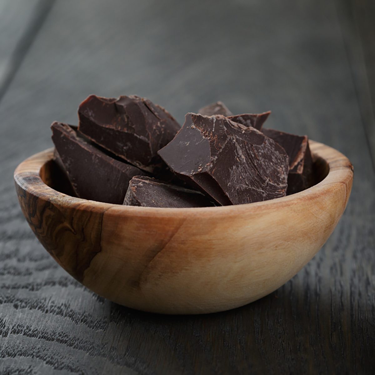 黑巧克力块装在木碗里，放在橡木桌上;