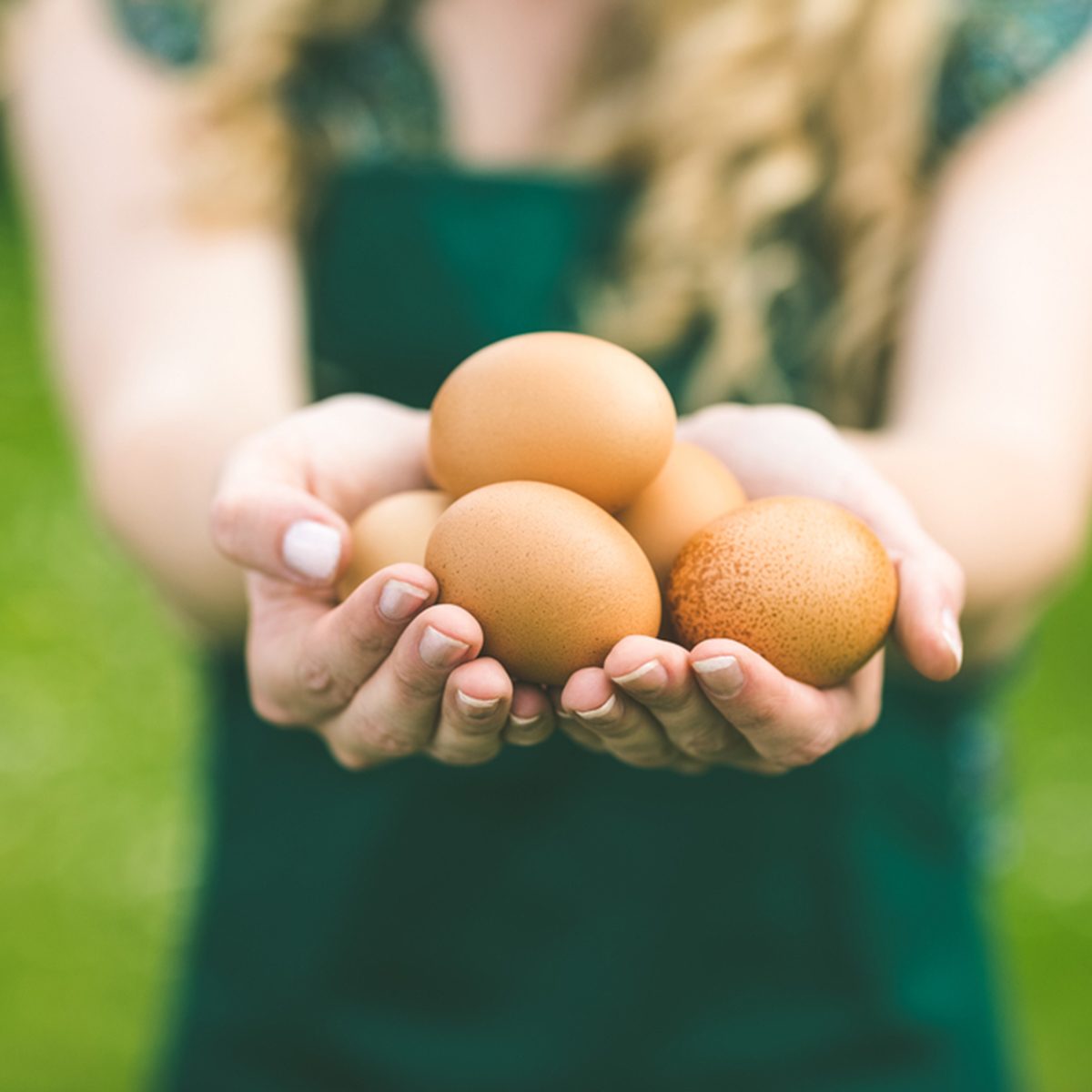 年轻女子站在草坪上展示鸡蛋