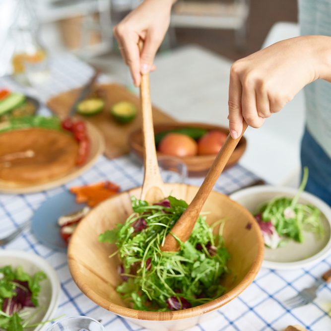 特写年轻女子混合绿色沙拉在木制碗在餐桌上与健康食品而准备家庭晚餐;伤风ID 734792491;工作(TFH、TOH、RD、BNB、CWM、CM): TOH超级食品