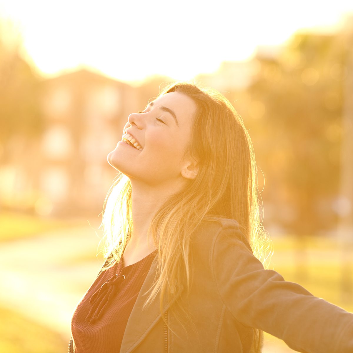 后灯的画像一个快乐的单身少女在日落公园呼吸新鲜空气温暖的黄灯和城市背景