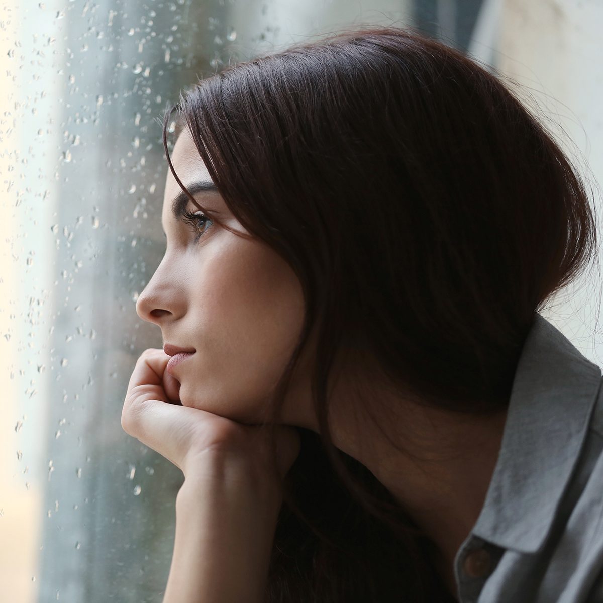 抑郁的年轻女子在家附近的窗口