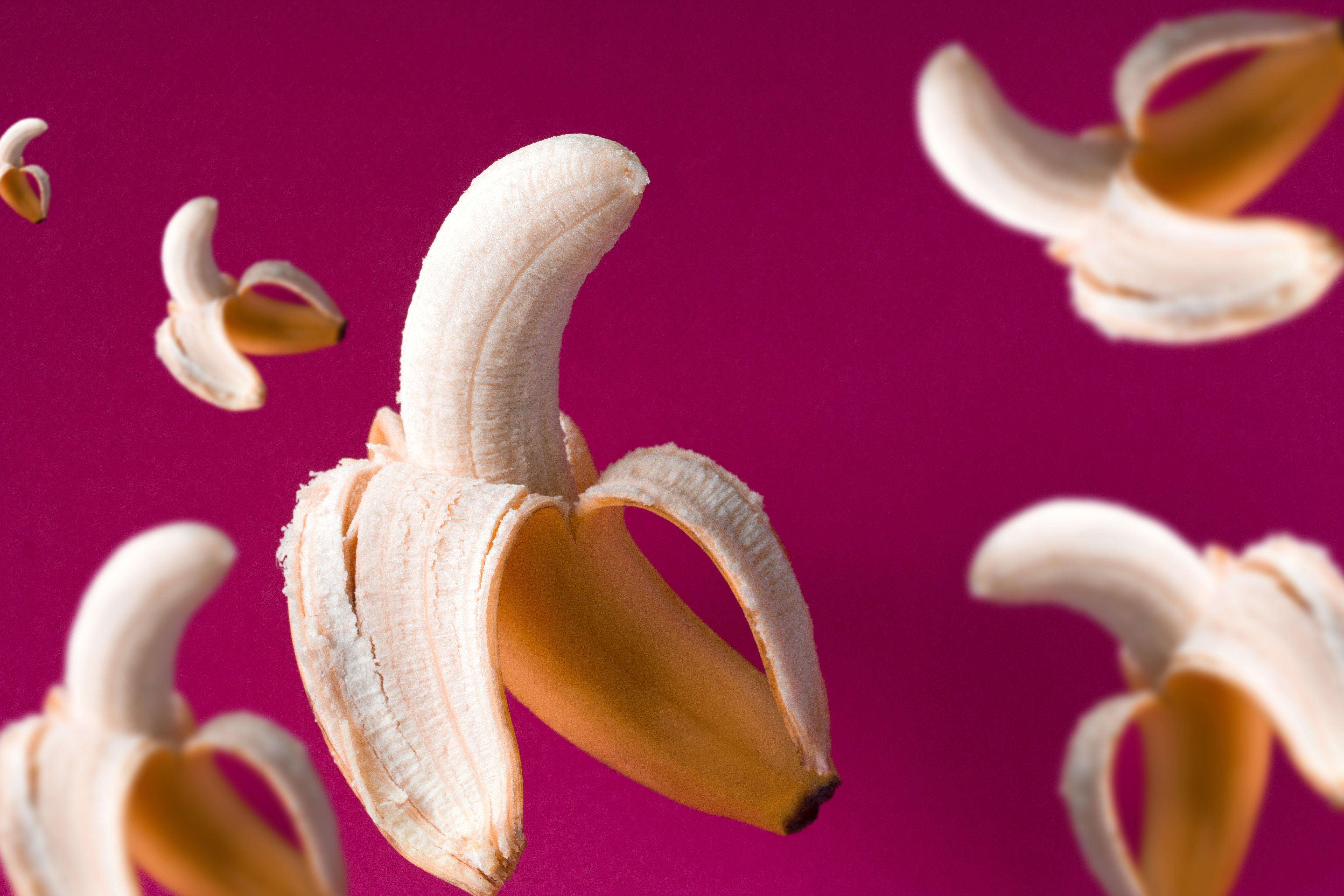 新鲜的飞行香蕉图案在一个充满活力的粉红色背景