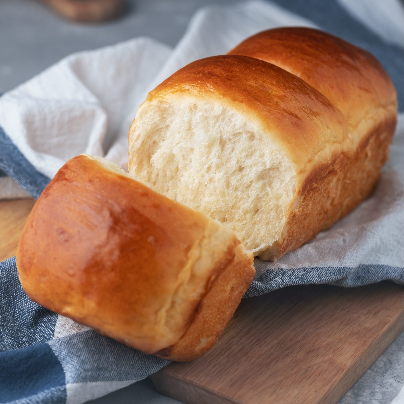 新鲜烘焙的自制北海道牛奶面包放在厨房毛巾上。日式松软面包。在家做饭。有选择性的重点。