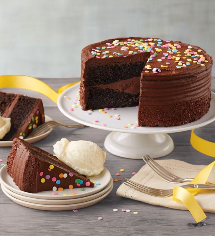 圆形巧克力蛋糕放在白色的餐盘上，旁边的小盘子上有一片巧克力蛋糕
