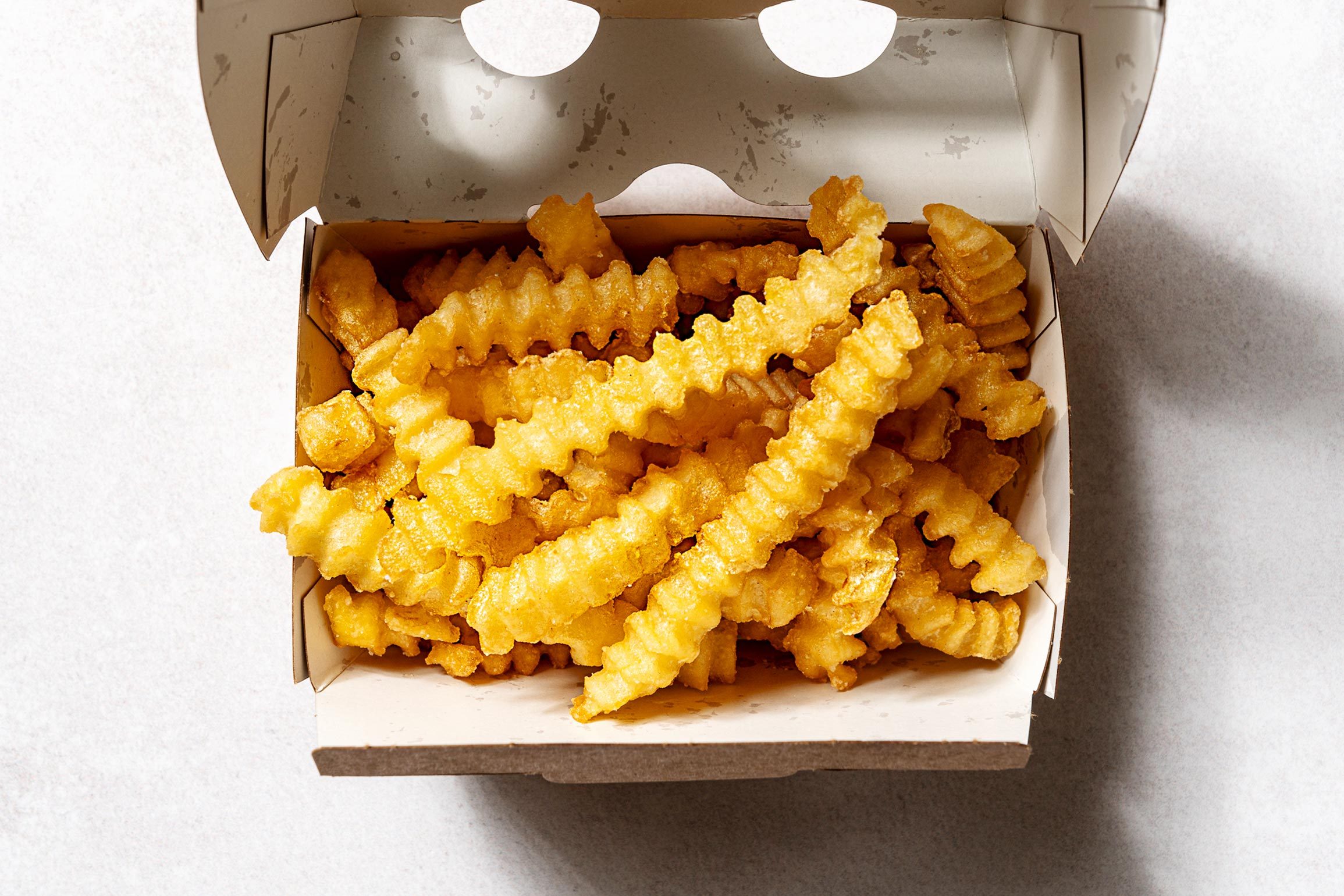 从纸板上的Shakeshack Crinkle Fries上方的观点，在白色背景上