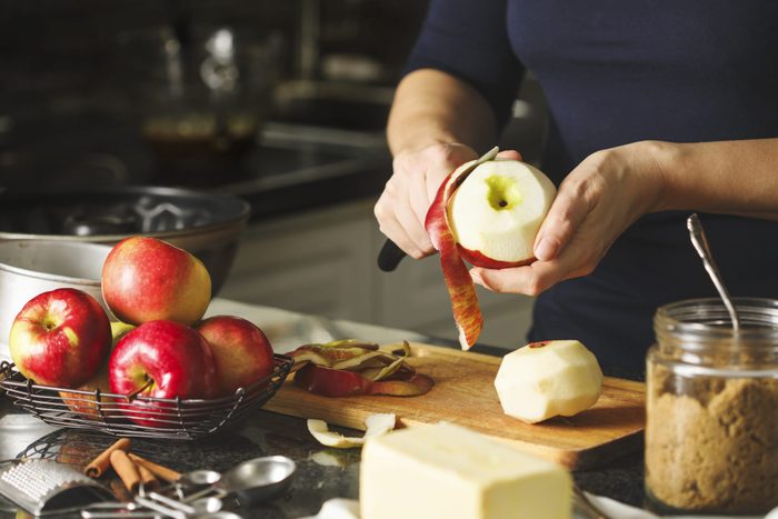 一个女人在厨房里做苹果蛋糕。剥苹果的女人