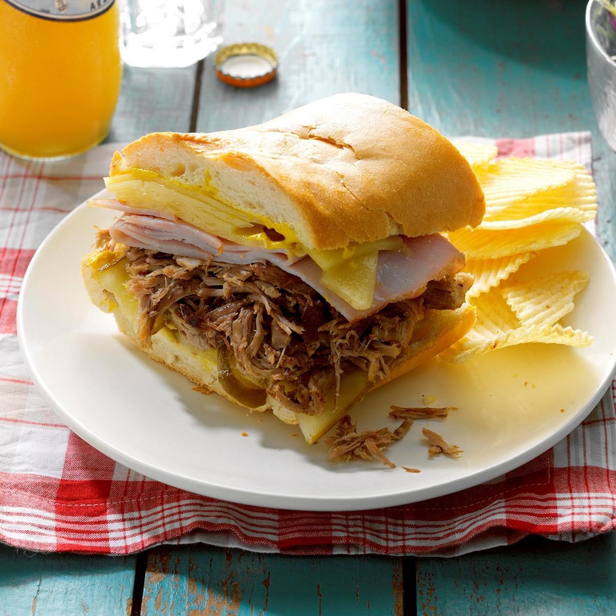 高压锅古巴拉猪肉三明治放在盘子里，薯条放在红色方格餐巾上