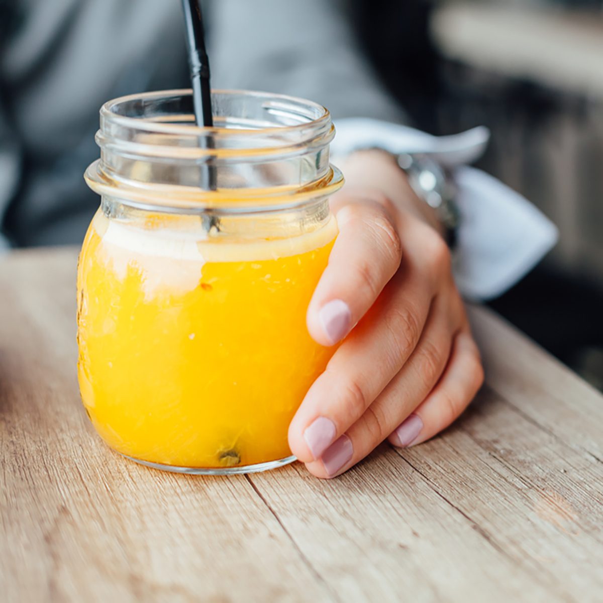 一瓶鲜榨橙汁。一名女子在咖啡馆喝橙汁。