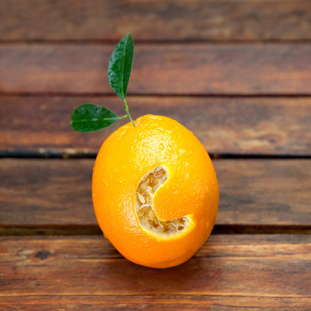 新鲜的橙子，上面刻着字母C，看起来像维生素C，放在木桌上。