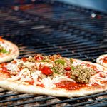 意大利披萨店的炭火烤架上烤着香肠和辣椒