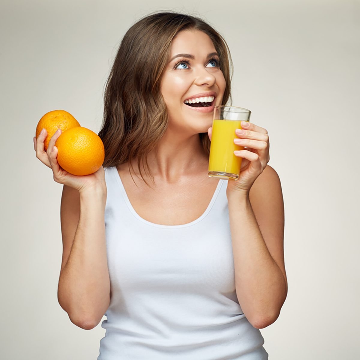 运动女人喝橙汁，拿着水果。