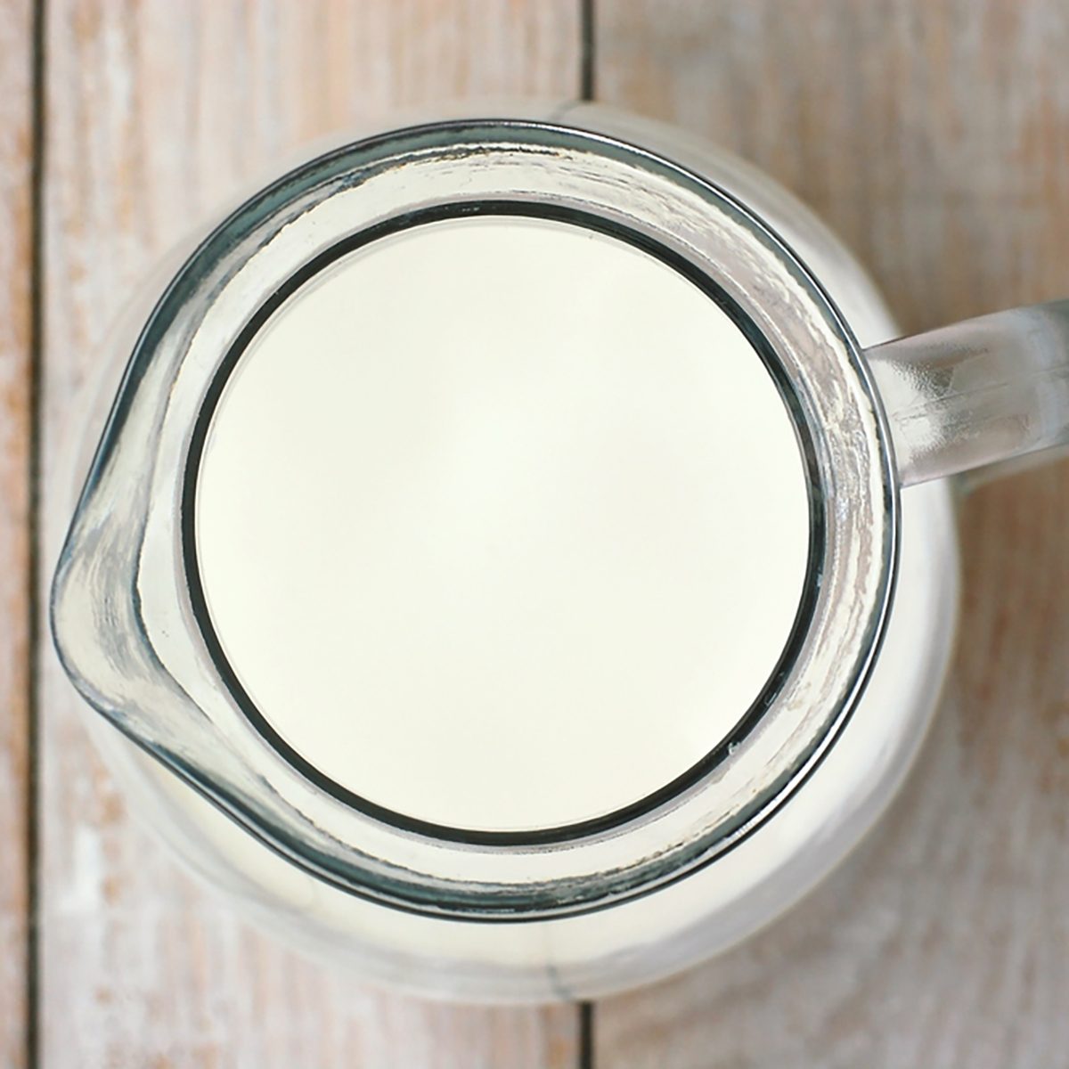 白色的牛奶在木制背景的罐子里