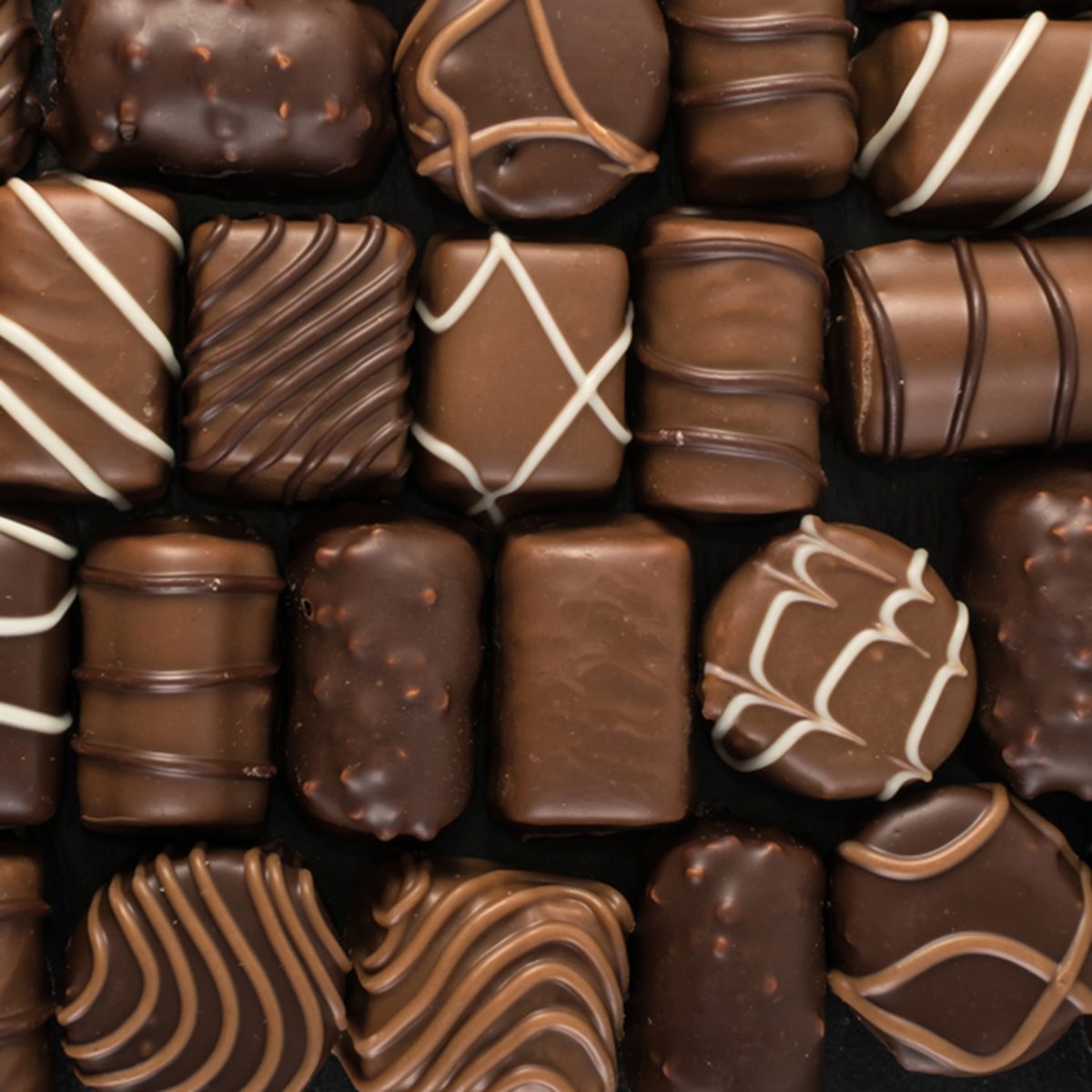 美丽的创意巧克力糖果在天然黑石背景。