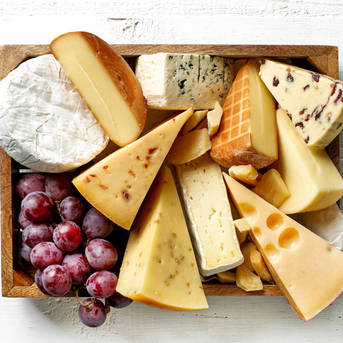 各种各样的奶酪放在白色木桌上的木箱里