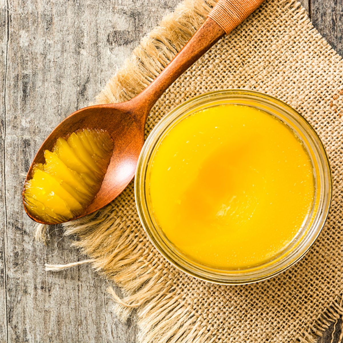 酥油或澄清黄油在罐中，木勺放在木桌上。