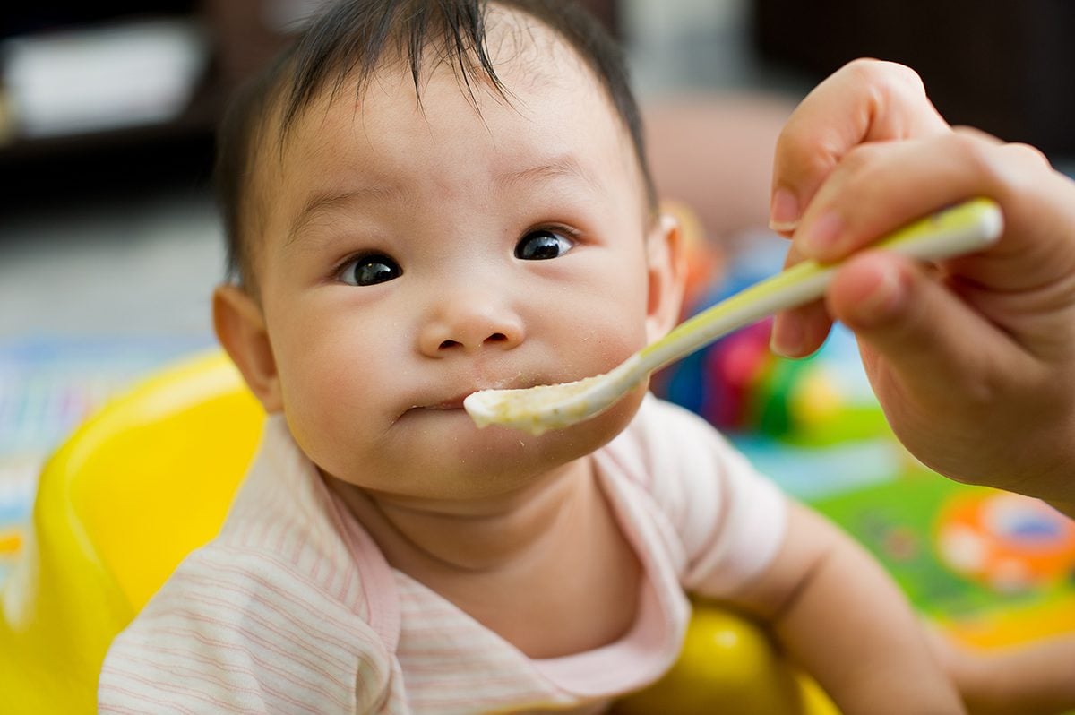 6个月大的东南亚华裔女婴坐在黄色座椅上，用勺子喂食;Shutterstock ID 78217849;Job (TFH, TOH, RD, BNB, CWM, CM): TOH婴儿固体食品