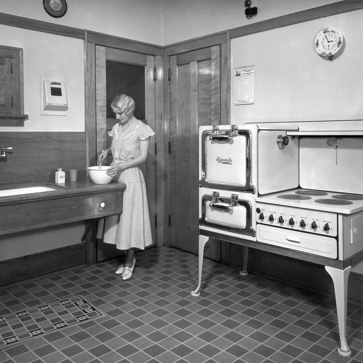 一个女人在她的厨房做饭，厨房配备了一个君主电炉。